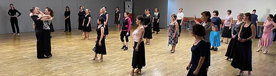 Skupinová lekce v sále, lektorský pár předvádí figuru